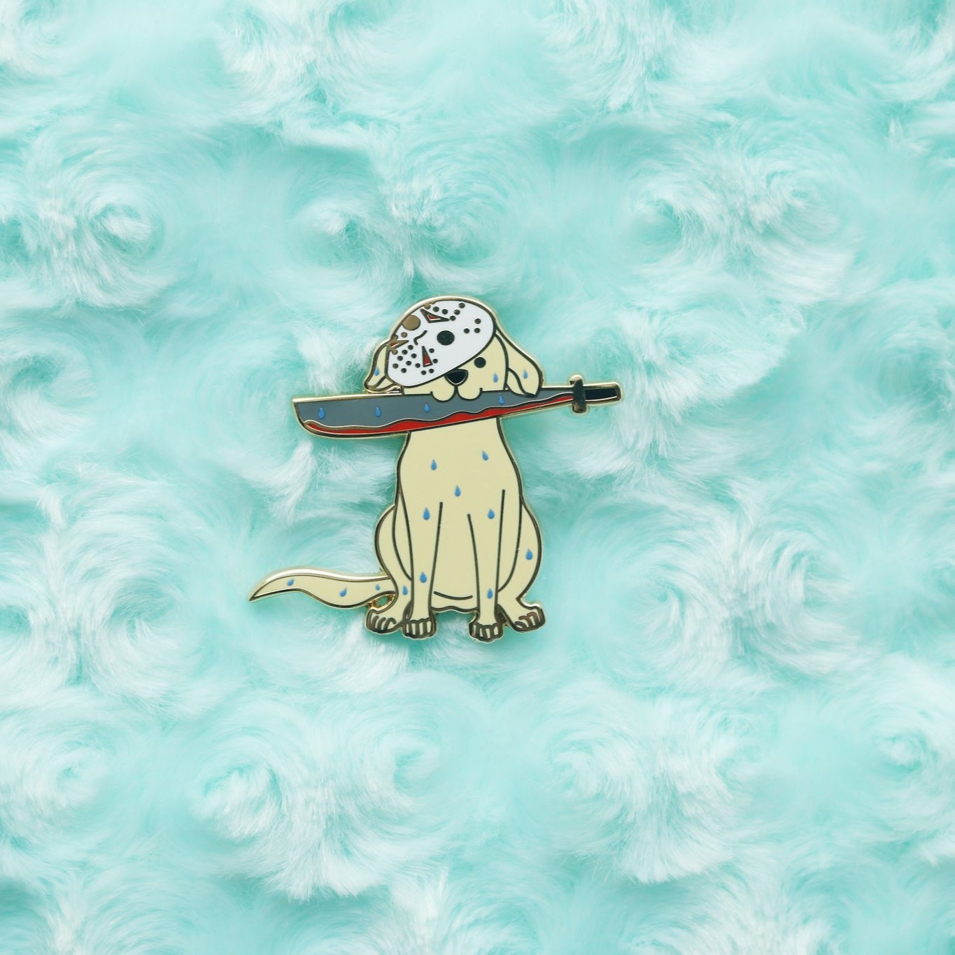 Enamel pin depicting a wet Yellow Labrador Retriever holding a bloody machete. A hockey mask covers half of it's face.