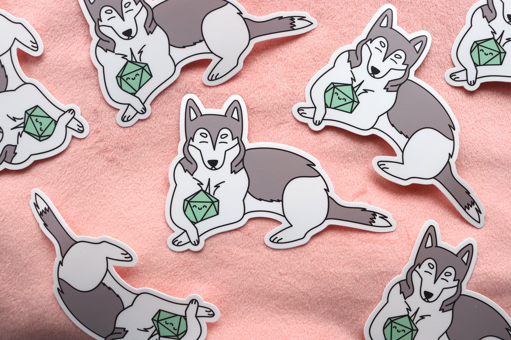 Pile of Gray and white husky sticker. Dog is holding a mint colored d20 between its front paws. Both dog and dice have happy faces with closed eyes.