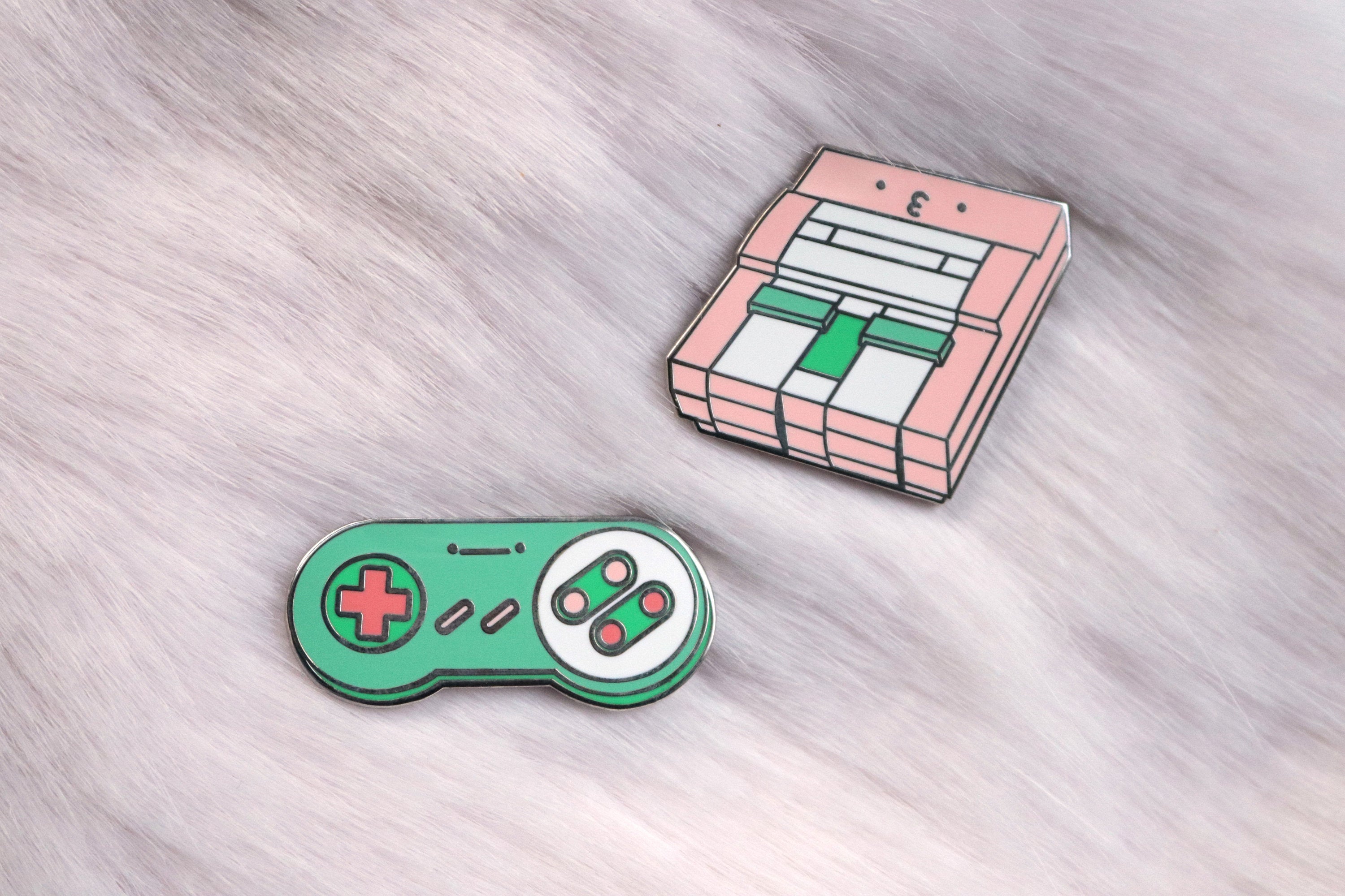 Pink SNES Consoles and Green SNES Controller Pins on Pink Fur Background