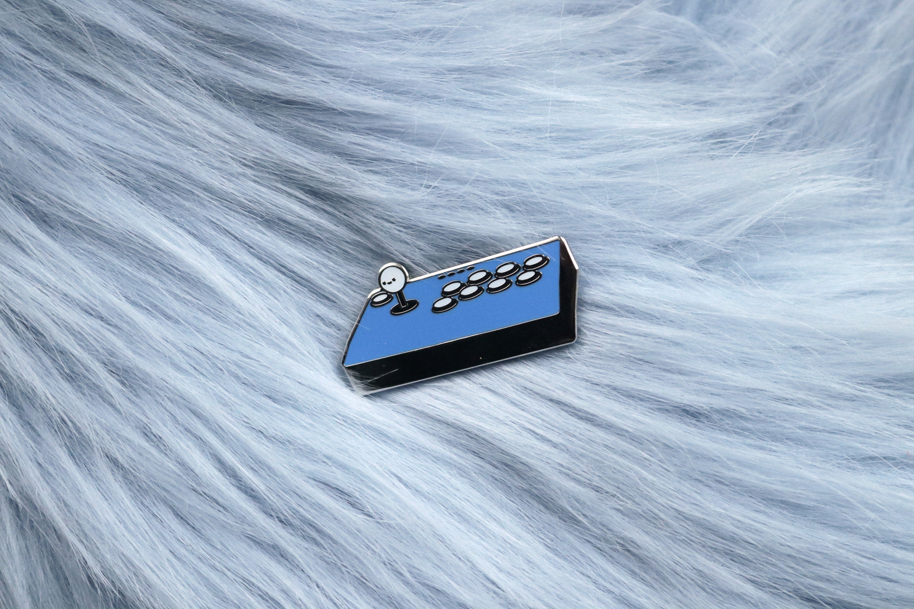 Blue Fight Stick Hard Enamel Pin on Blue Fur Background