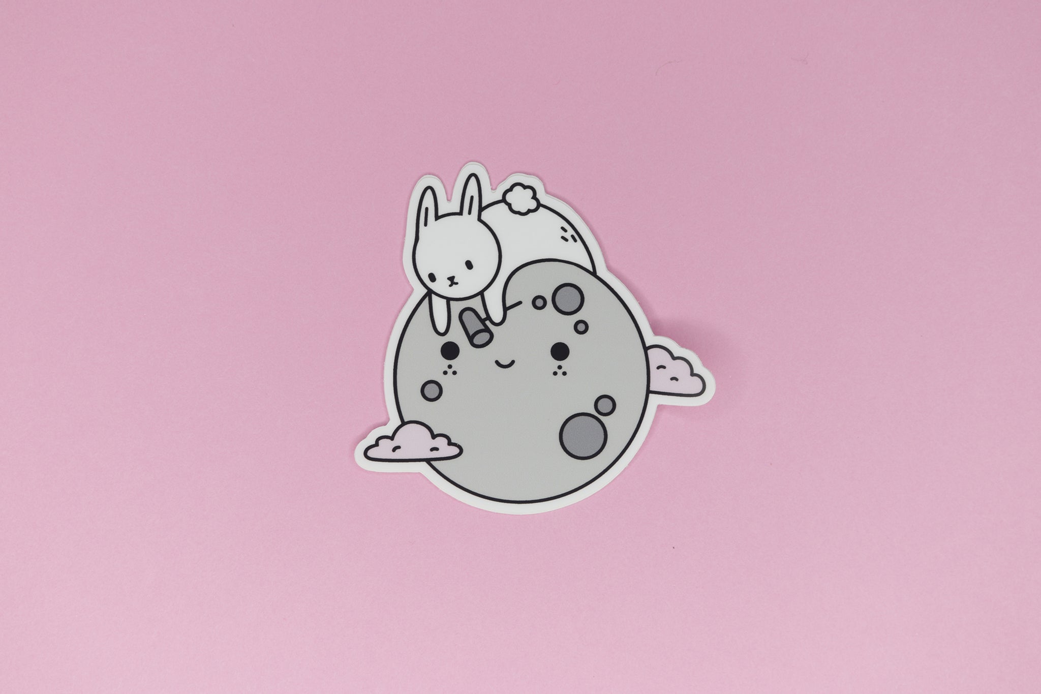 sticker of white bunny on grey moon with pink clouds